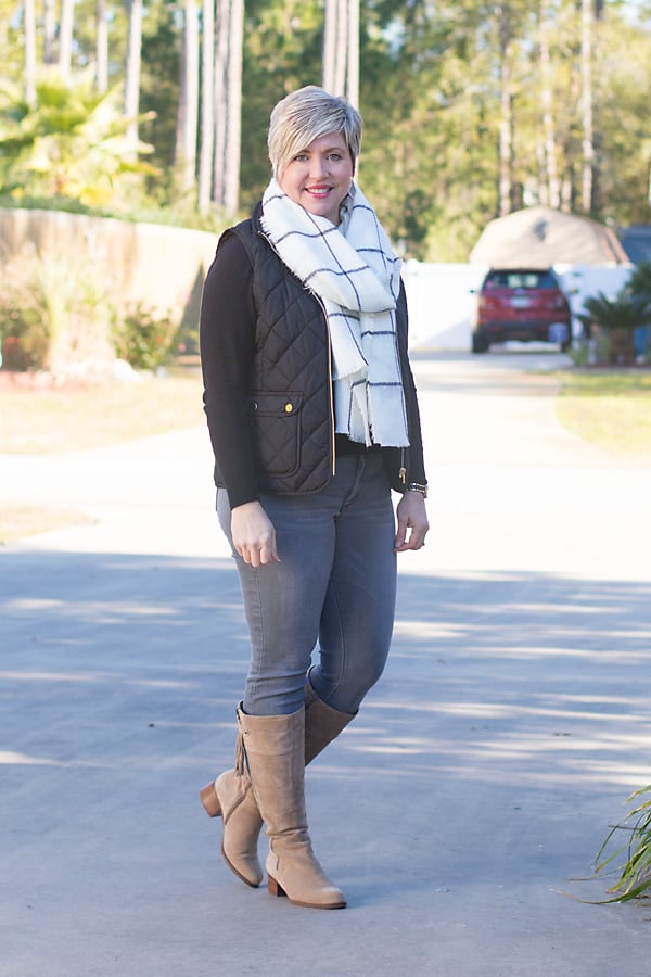 Over 40 fashion blogger in winter outfit with tall boots, vest and scarf.
