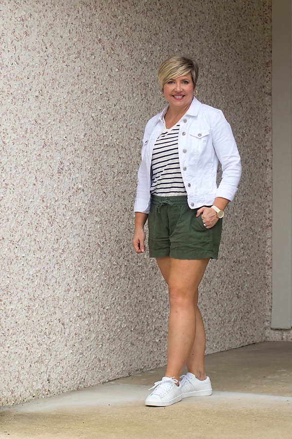 white denim jacket outfit with olive shorts and sneakers